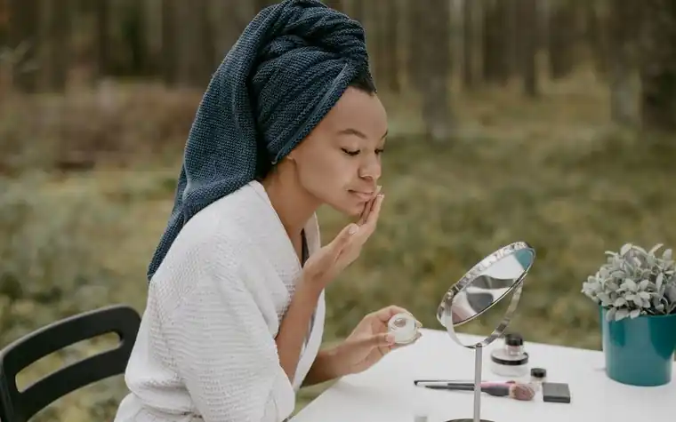 A woman applying face cream as part of an outdoor skincare routine