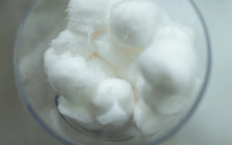Soft white cotton balls gathered in a glass container