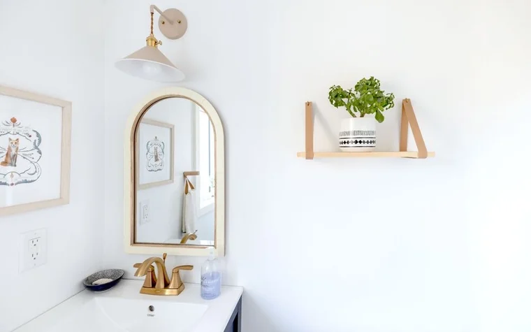 A bright, minimalist bathroom with a gold-framed mirror