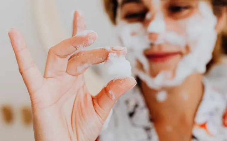 Close-up of water droplets and foam from a cleansing product on skin