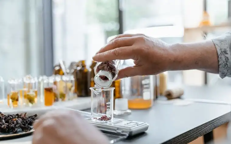 Lab technician in gloves measuring cosmetic ingredients into a glass beaker