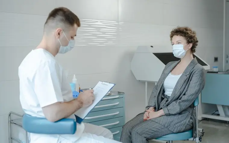 Doctor in a face mask consulting with a patient in a clinic examination room