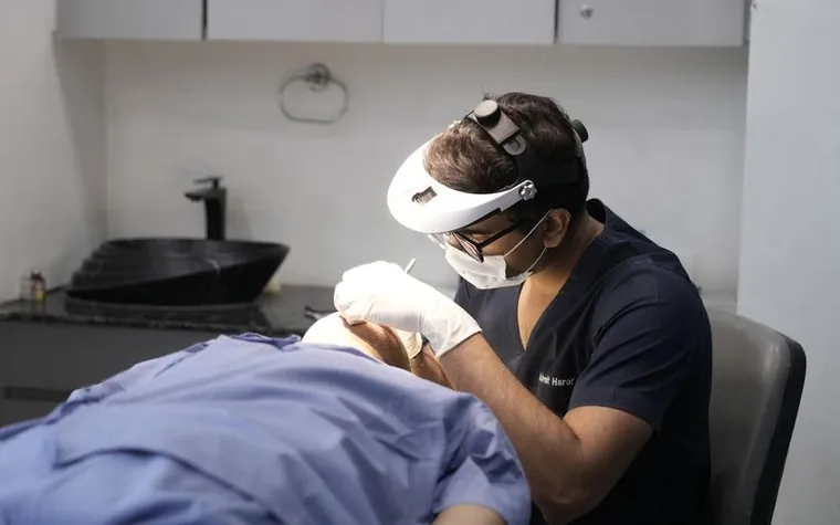 Esthetician performing a skin treatment on a client lying down in a clinic