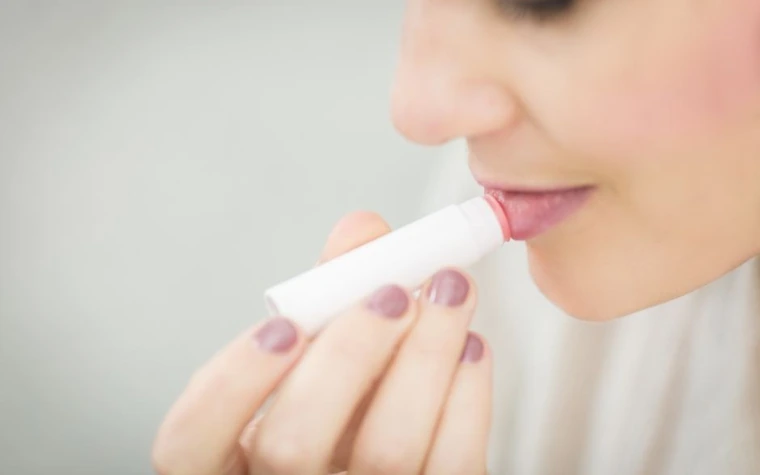 Close-up of a woman applying a white lip balm stick to her lips