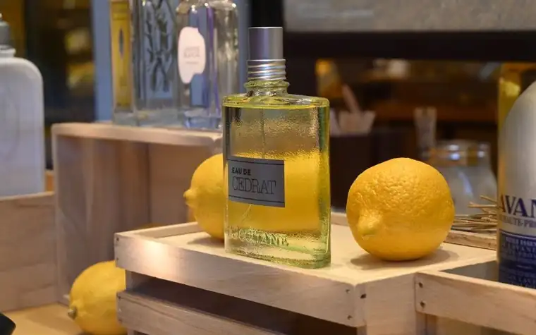 Eau de Cedrat perfume bottle displayed beside fresh lemons on a wooden shelf