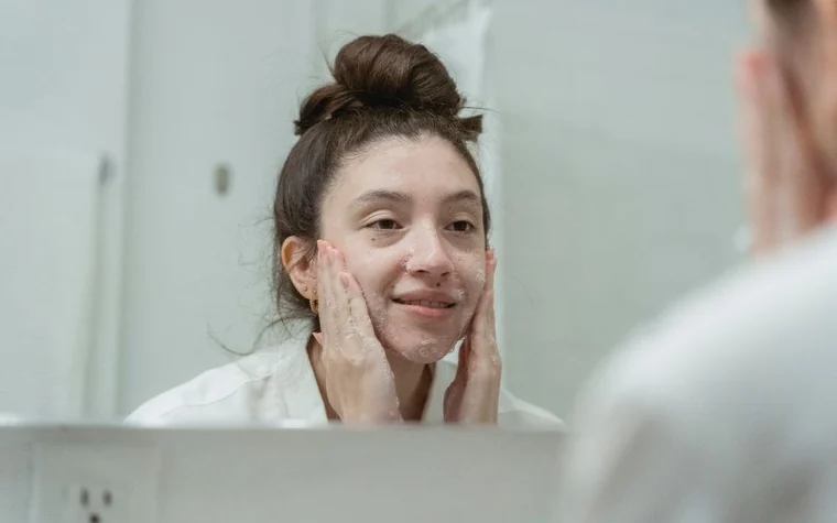 A woman checking her skin in a bathroom mirror