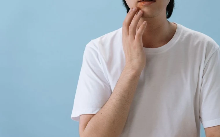 A close-up of a man gently touching his cheek