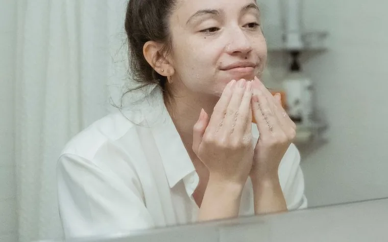 A woman washing her face with cleanser at a bathroom sink