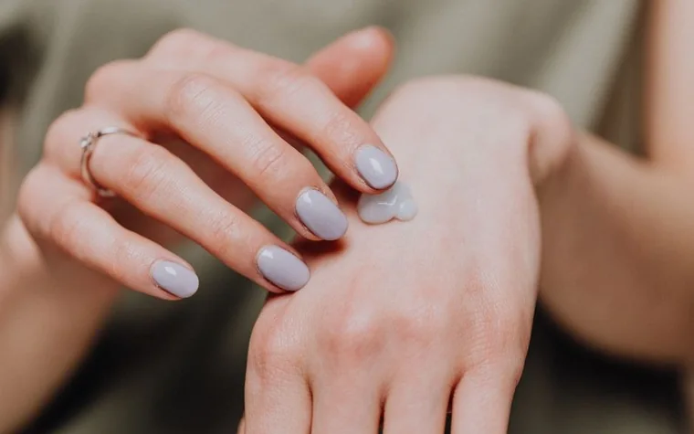 A hand applying moisturizer to the forearm