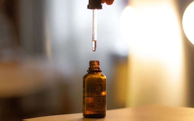 A dropper above an amber glass serum bottle