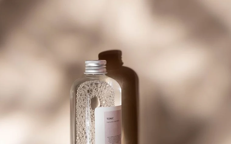 A glass toner bottle in a softly lit studio setting