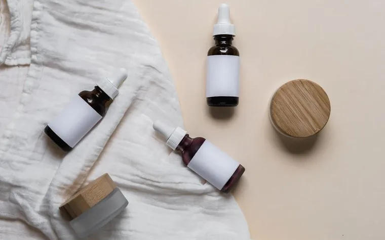 Glass skincare bottles arranged on a textured fabric surface