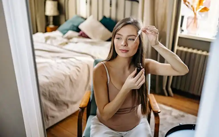 A woman applying facial serum with her fingertips