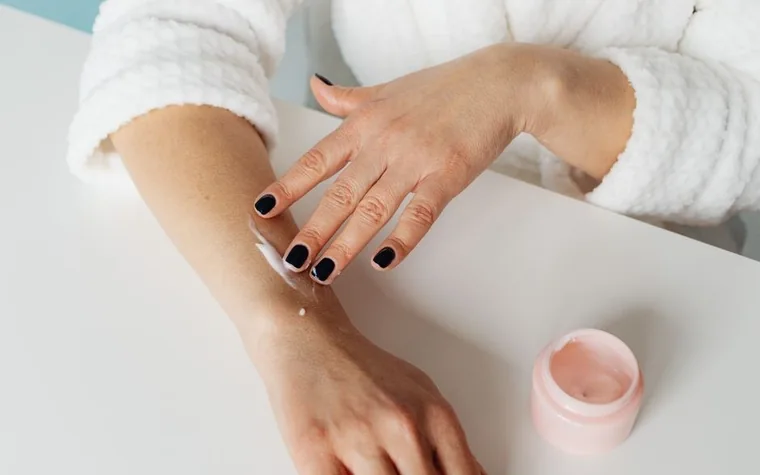 Close-up of hands applying moisturizer to the skin