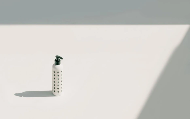 Minimalist pump bottle casting a long shadow on a bright surface