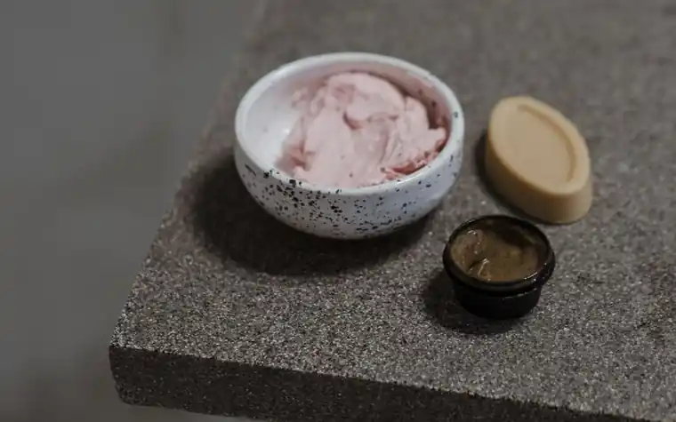 Pink cream in a ceramic bowl next to a bar of soap