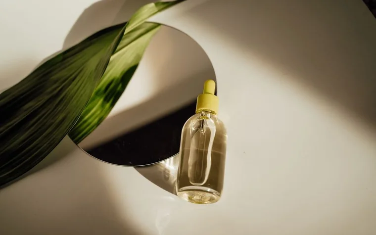 Amber dropper bottles on a mirror surrounded by dried flowers