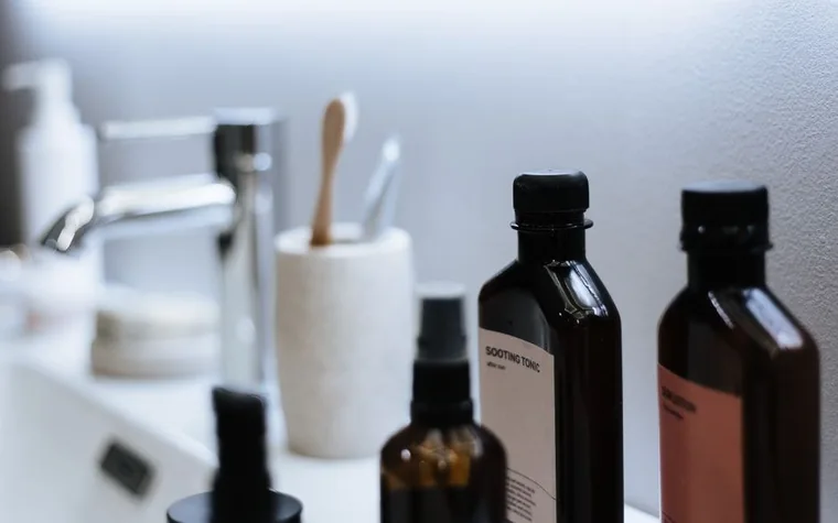 A modern bathroom sink counter with cosmetic bottles arranged neatly