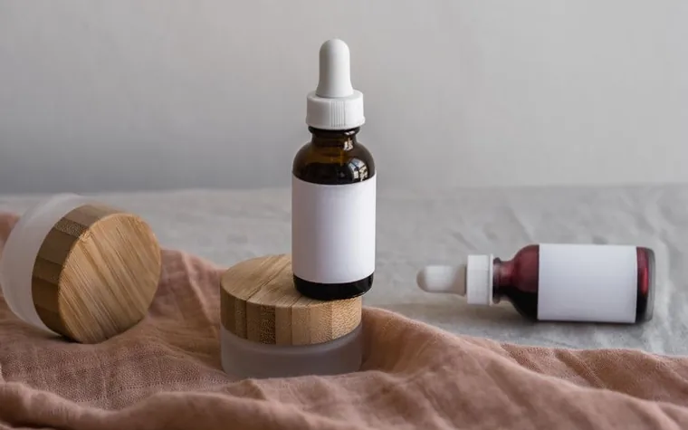 A single serum dropper bottle standing on folded fabric