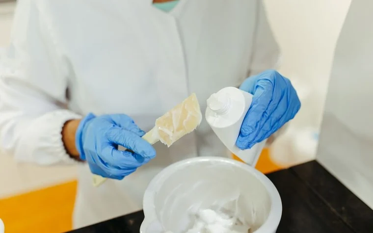 A gloved technician mixing a cosmetic cream in a laboratory