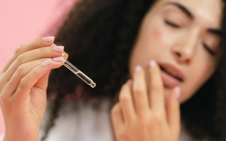 Woman applying serum from a dropper near her face