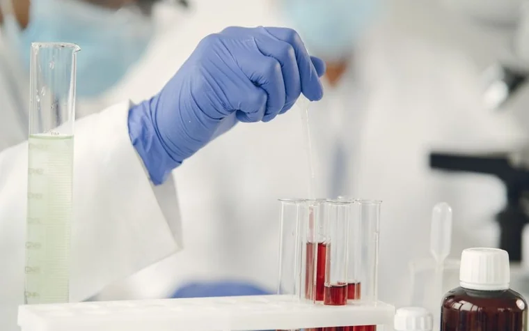 Scientist in gloves using a pipette with test tubes in a research lab