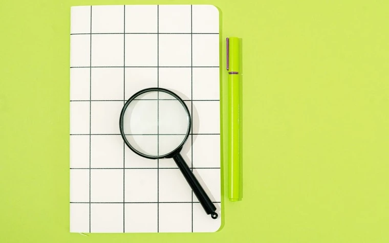 A magnifying glass resting on a gridded notebook