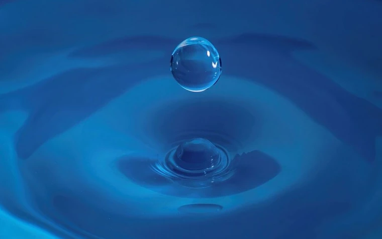 A blue water droplet on rippled water