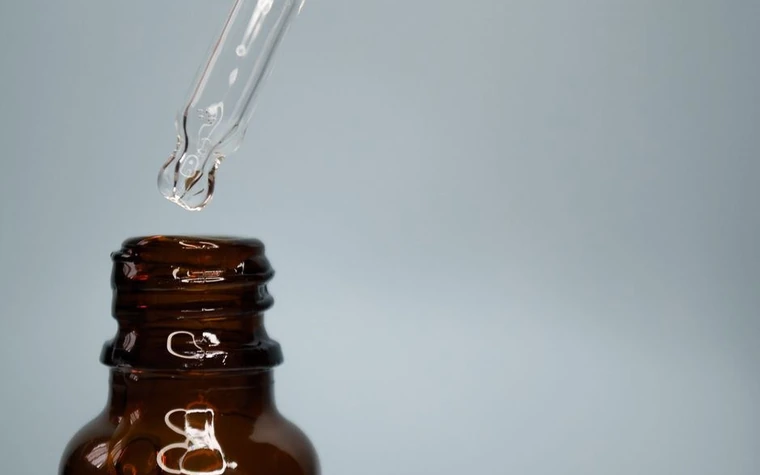A glass dropper held above an amber serum bottle