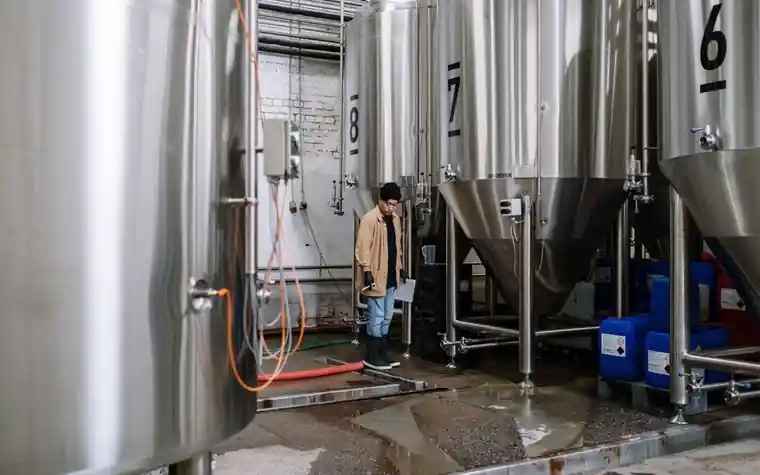 Rows of stainless steel fermentation tanks in a brewery hall