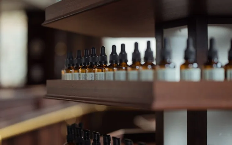 Shelves lined with small amber glass dropper bottles in a shop, with the nearest bottles in focus