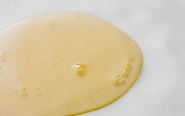 A clear oily droplet spread on a white surface