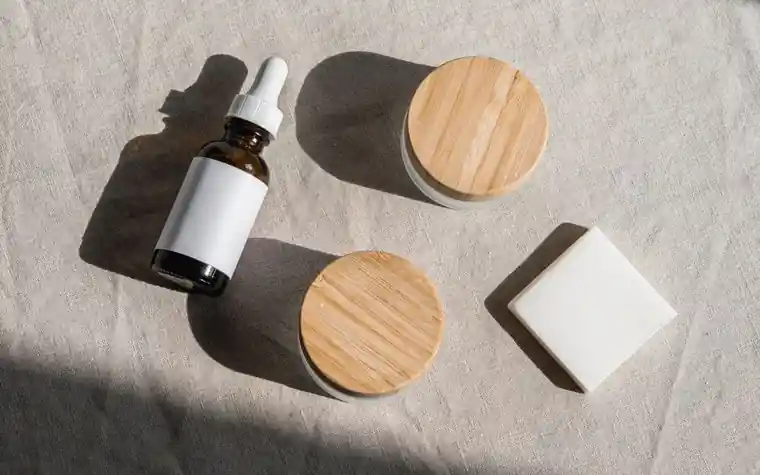 A dropper bottle and wooden-lid jars on a linen cloth