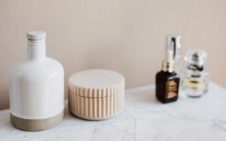 Skincare bottles and a jar on a marble surface