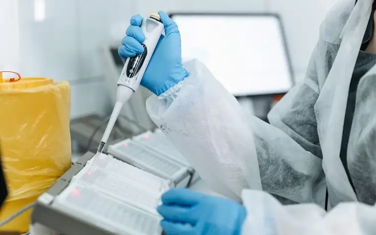 A scientist using a micropipette at a laboratory bench