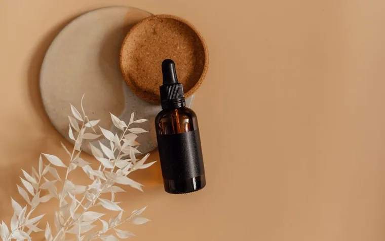 An amber dropper bottle styled on a warm-toned flat lay