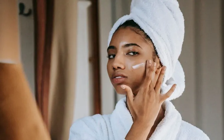 A person applying a few drops of skincare product to their fingertips