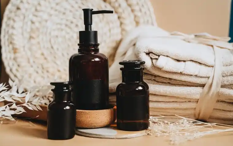 Amber skincare bottles arranged next to neatly folded white towels