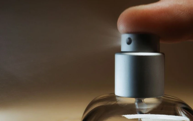 Close-up of a finger pressing a spray bottle nozzle