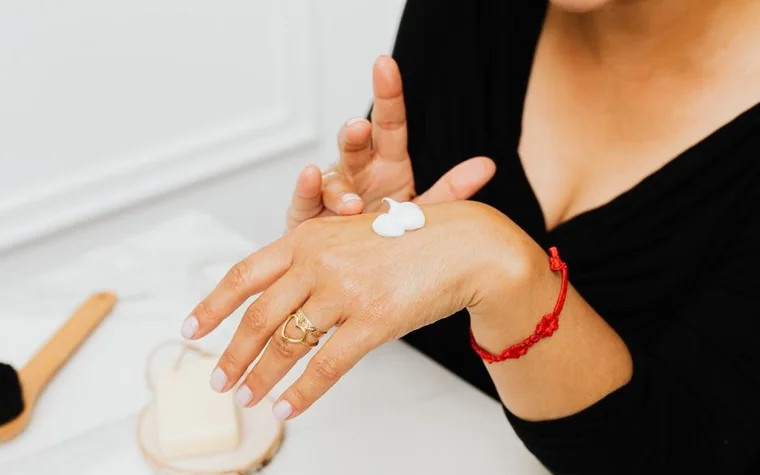 A woman applying a dab of white cream to the back of her hand