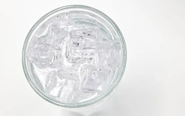 A glass of water filled with ice cubes seen from above