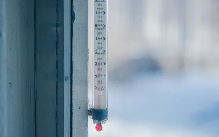 A thermometer mounted on a frosty window frame