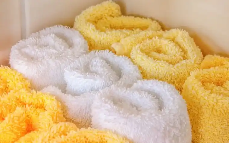 Rolled white and yellow towels stacked together