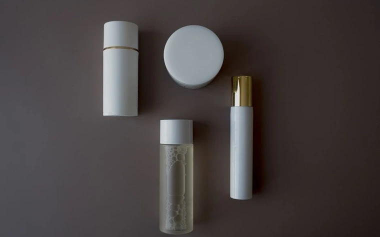 Skincare bottles arranged on a plain grey surface, seen from above