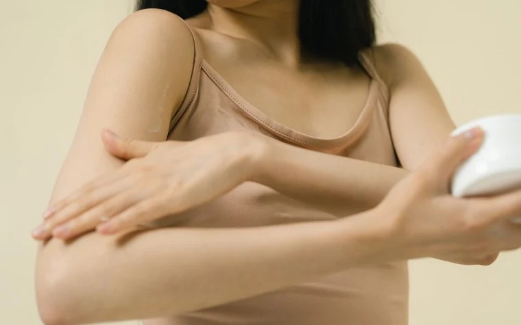 A woman applying a skincare product to the inside of her arm