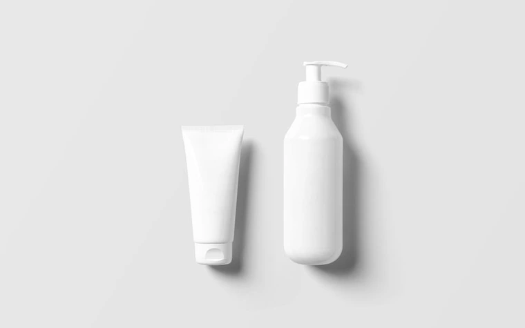 A minimalist white pump bottle and cream tube on a light background