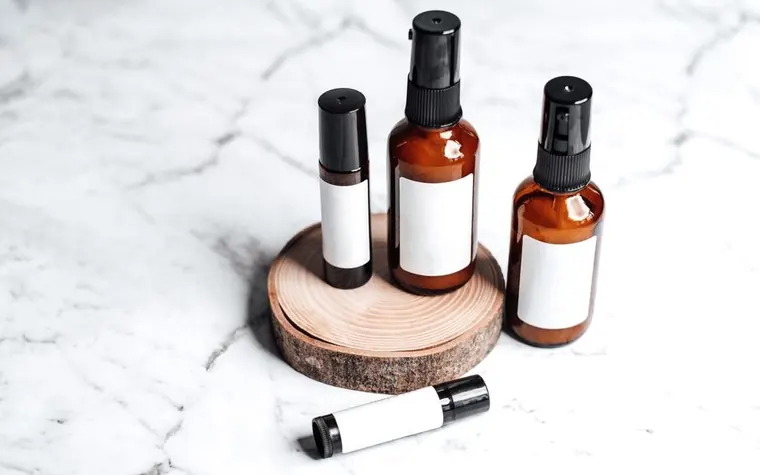 Amber skincare bottles arranged on a marble and wood surface