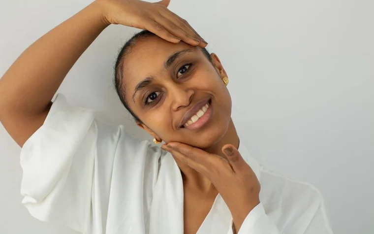 Woman smiling with her hand resting against her cheek and forehead