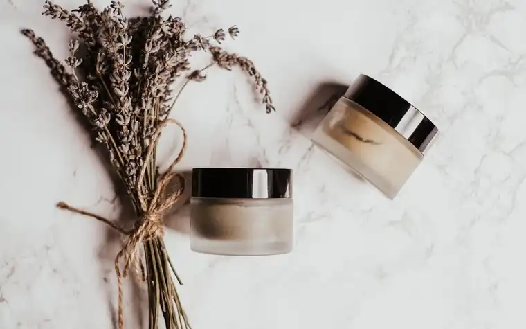 Skincare jars and dried lavender arranged on a marble surface