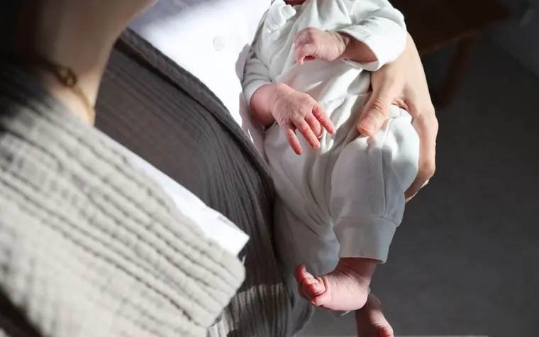 Mother cradling her newborn baby in a sunlit room